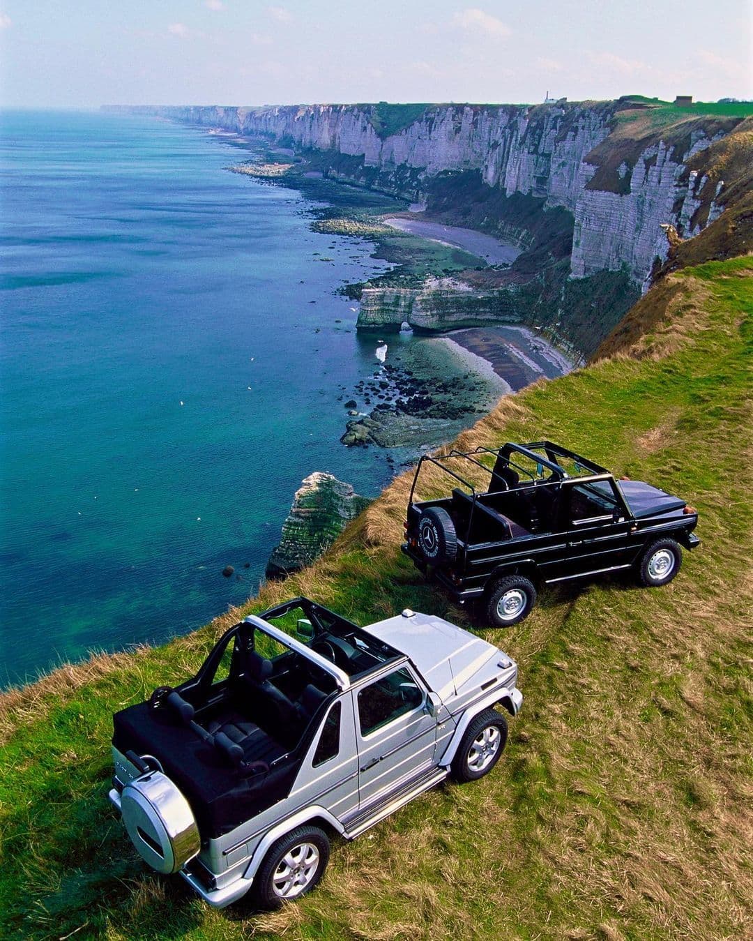Two classic four wheel drives above a dramatic coastline
