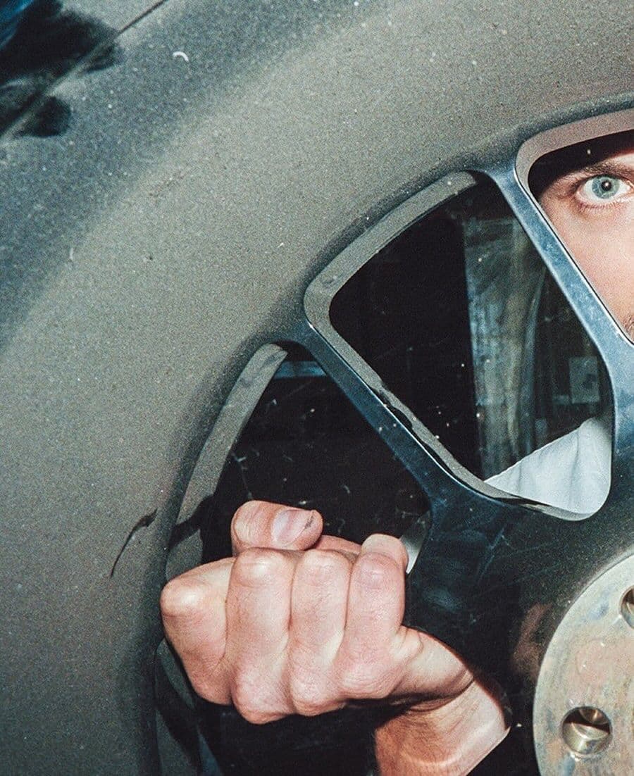 A driver in a helmet seen through a car window