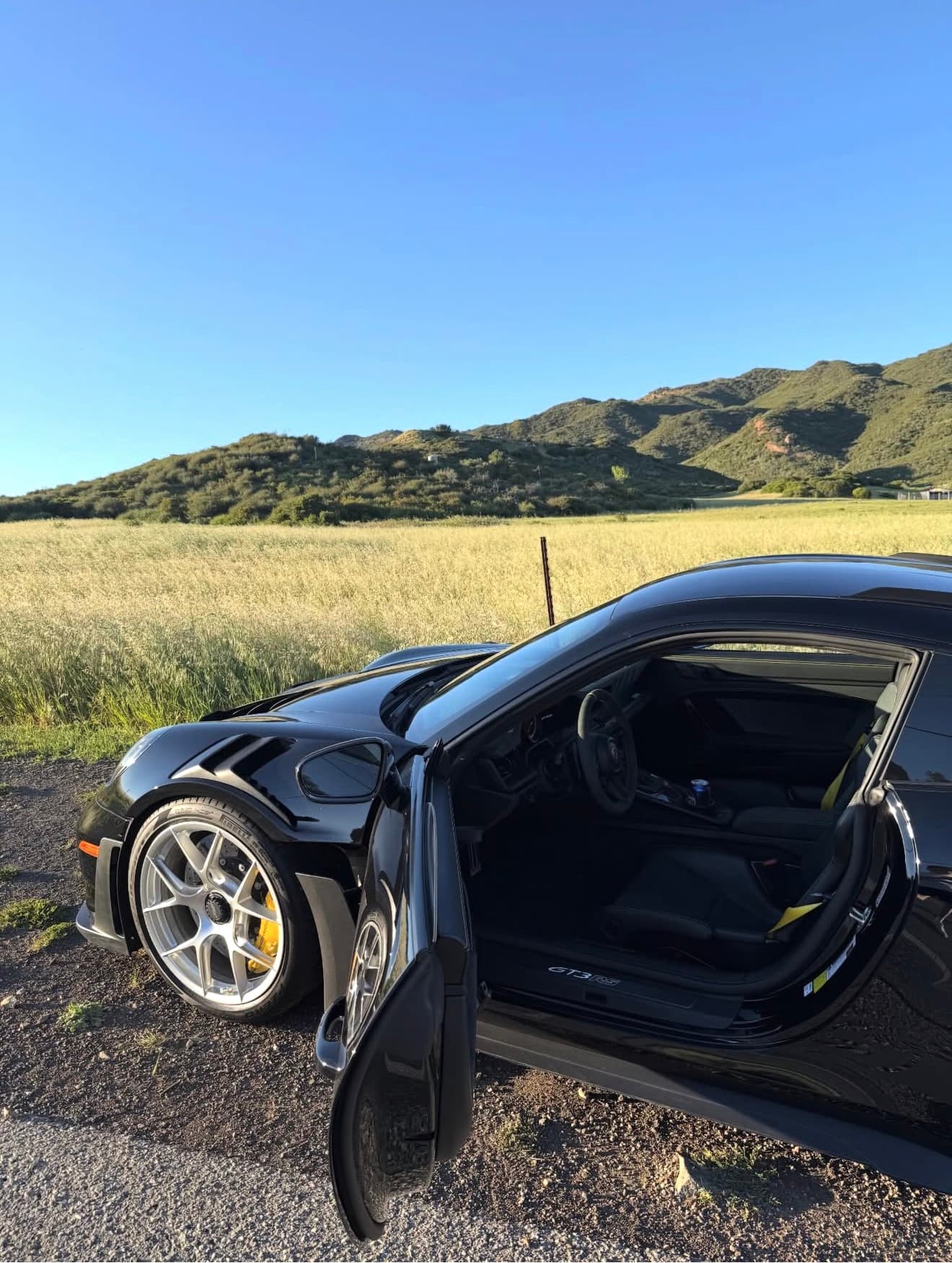 A black collector car photographed in an open landscape
